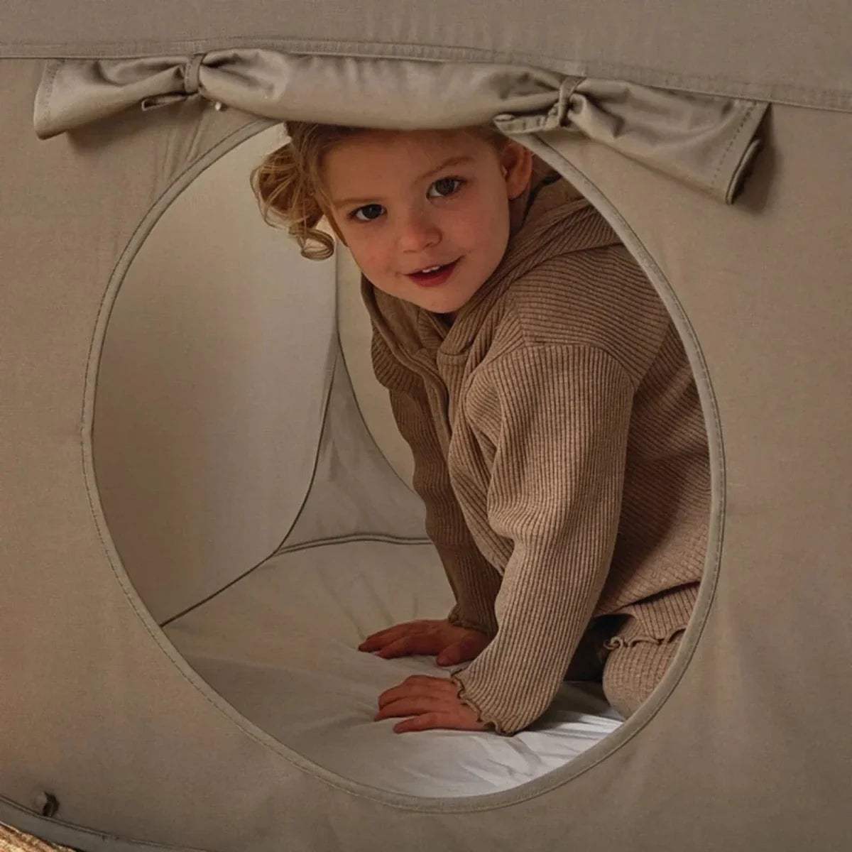 Gray tunnel end with round entrance and beige-and-tan striped fabric panel