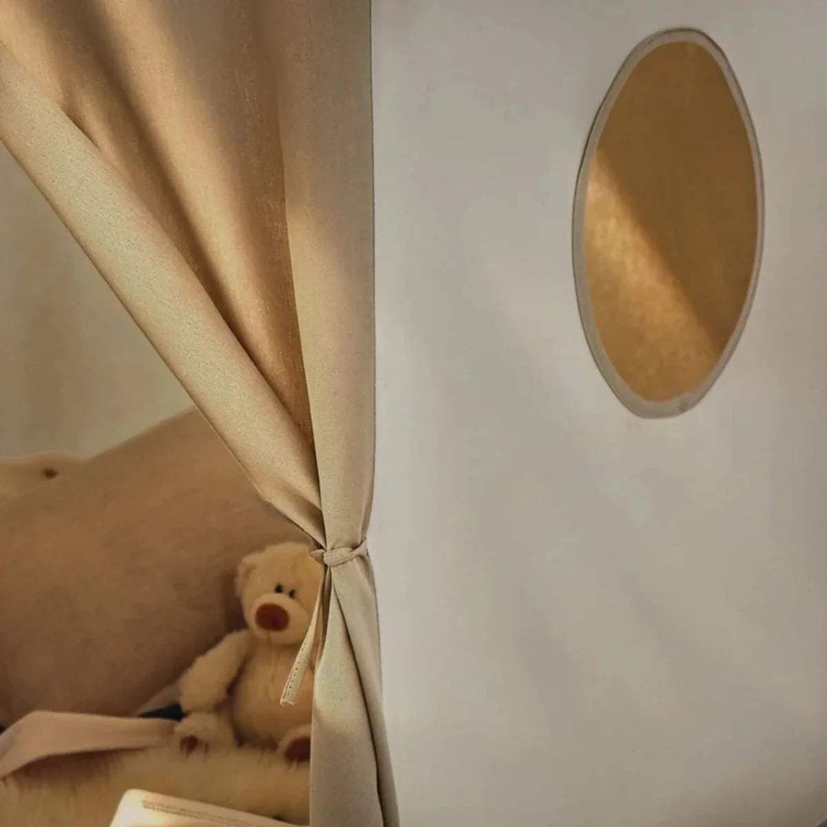 Side window cutout and tied fabric corner inside a cream play tent
