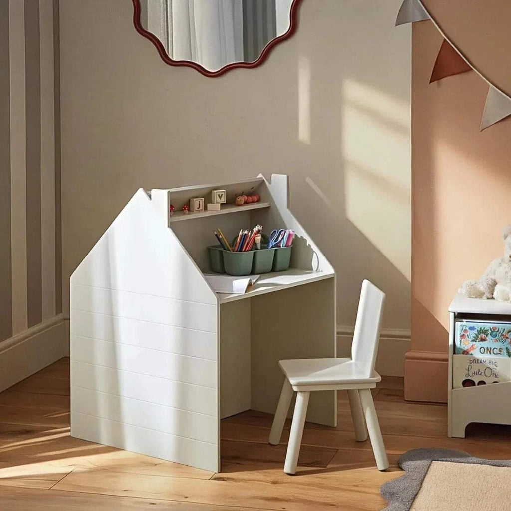 White playhouse storage desk with open interior shelves and small chair