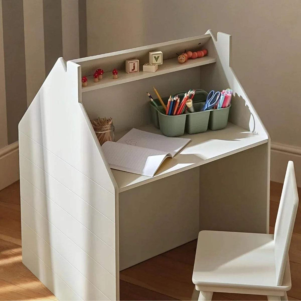 White playhouse storage desk with desk surface, open shelves, and chair
