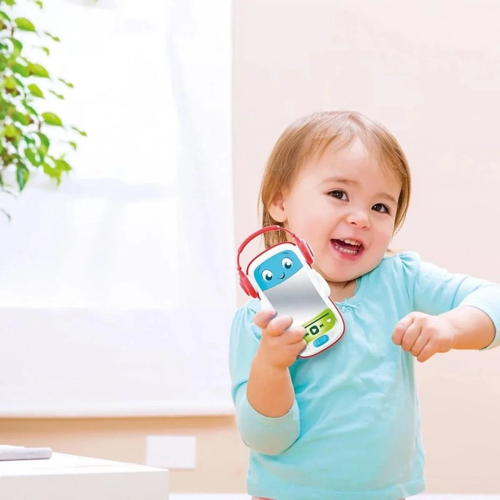 Baby holding a musical pod toy with red headphones and blue face
