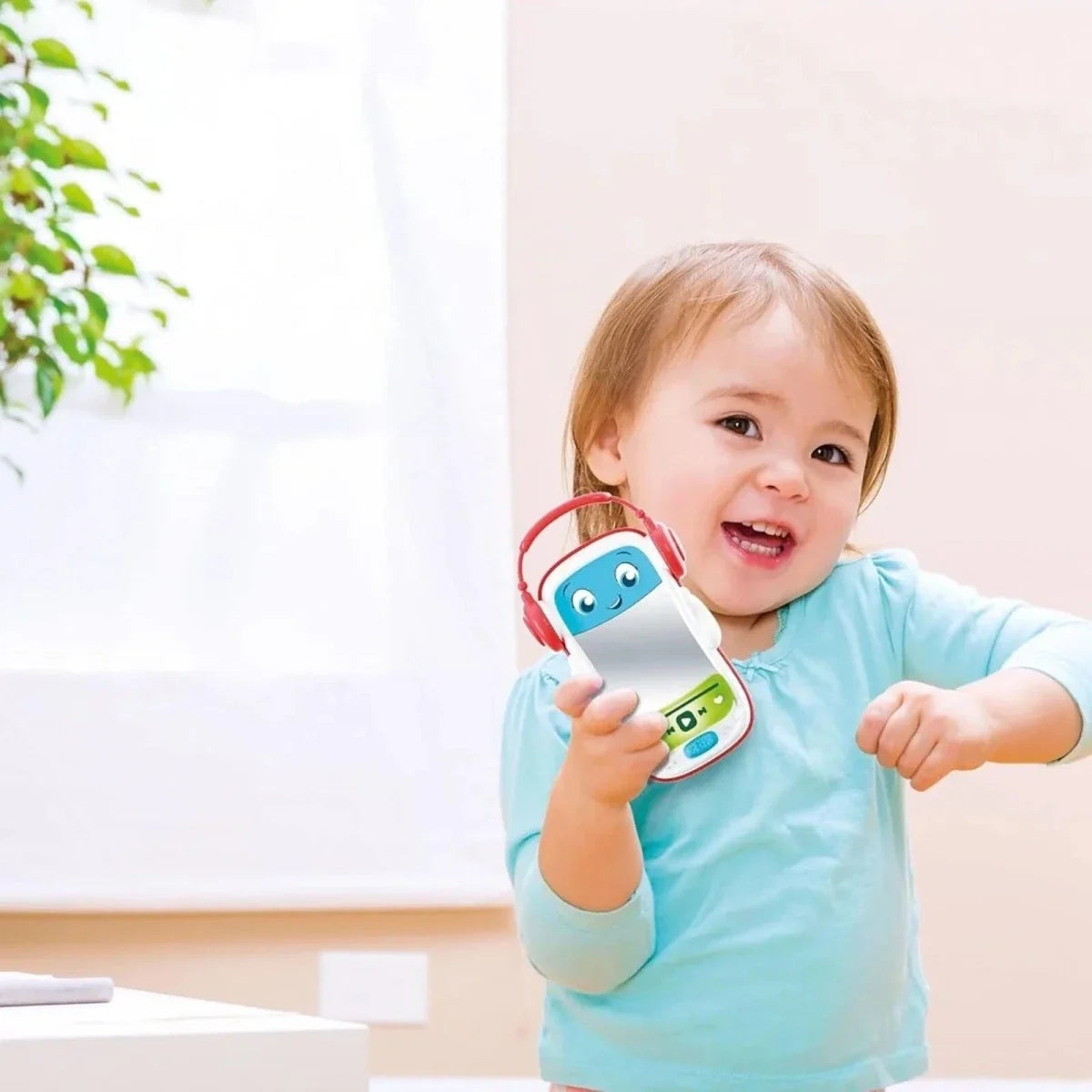 Baby holding a musical pod toy with red headphones and blue face