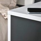 Grey side table corner detail with smooth edge and metal support for stability.