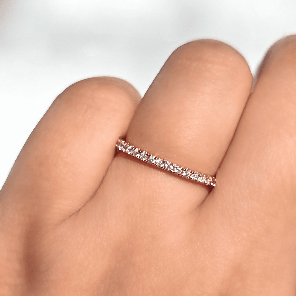 Rose gold eternity ring with pavé stones on a finger
