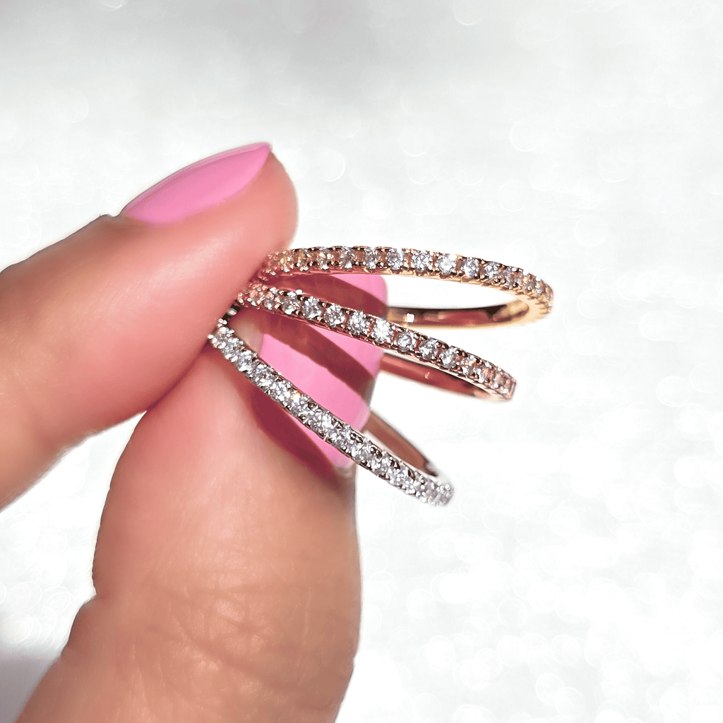 Rose gold eternity ring with pavé-set stones, shown between fingers