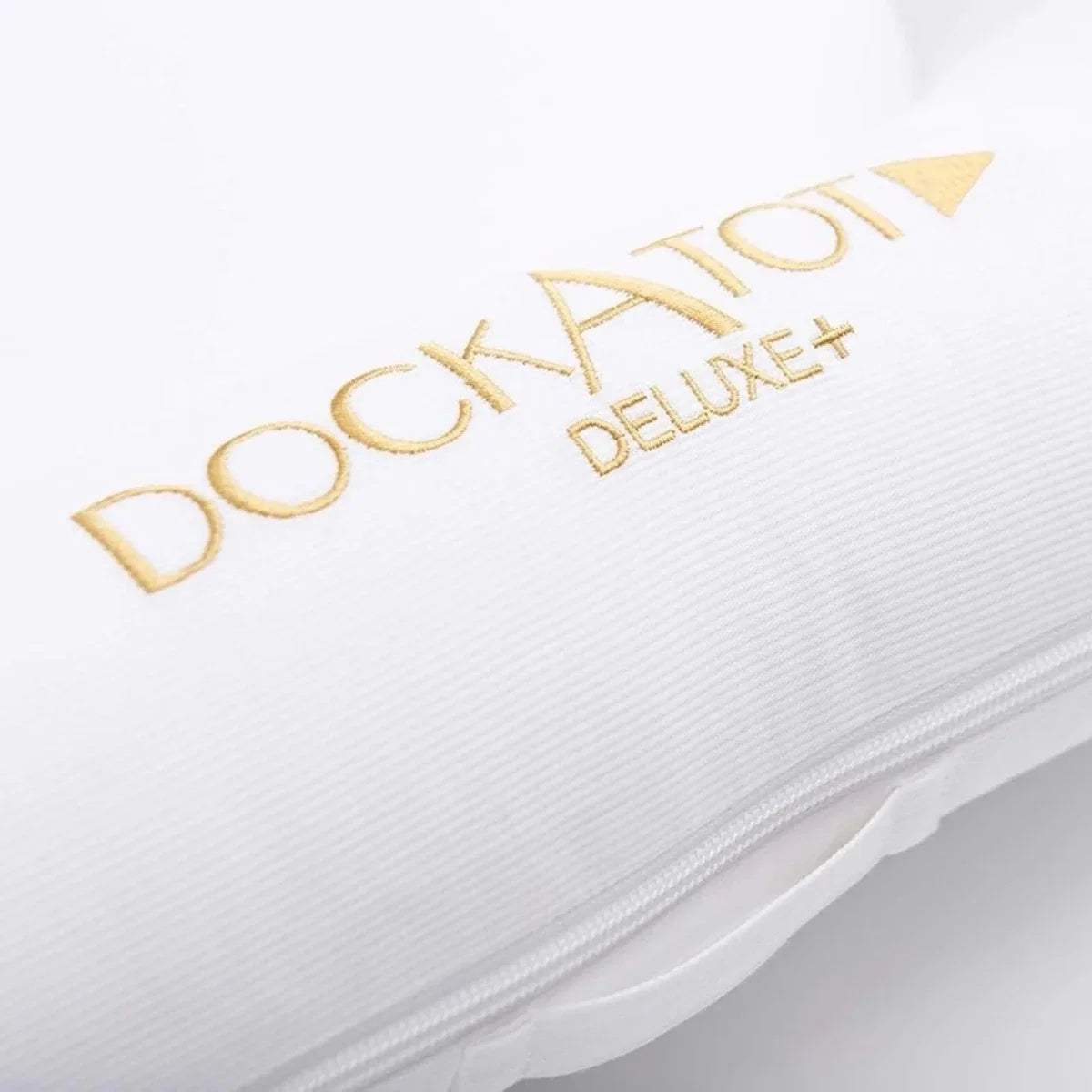 White fabric baby dock cover with gold 'DockATot Deluxe+' logo text