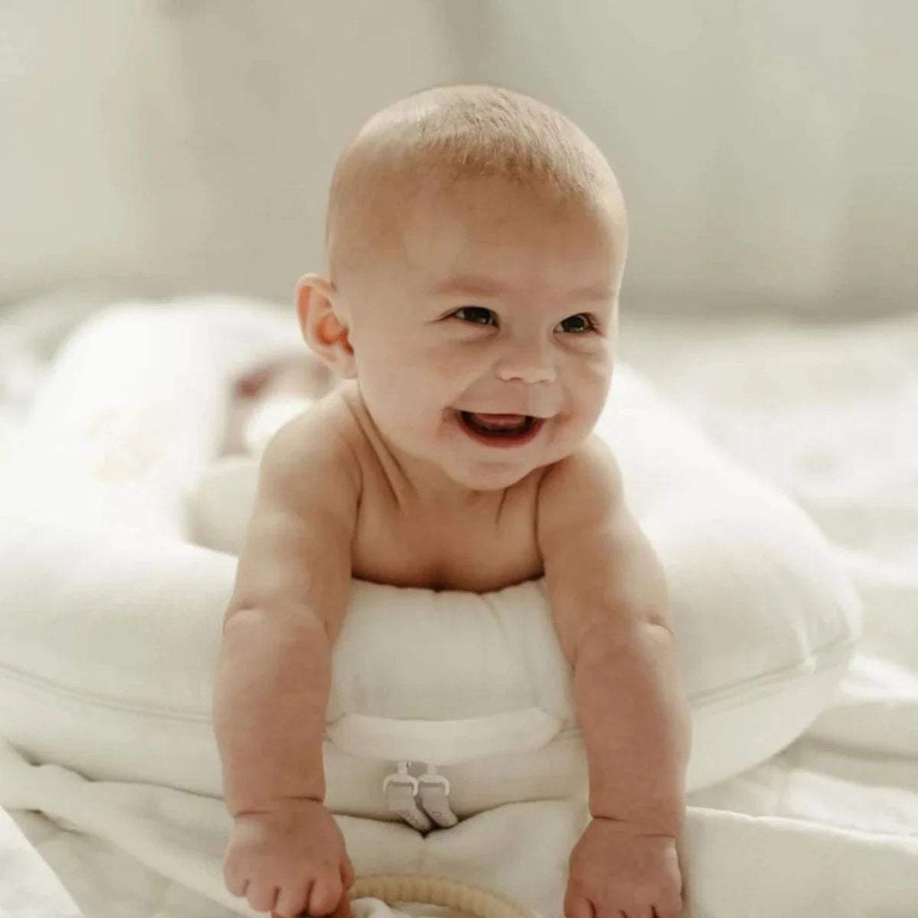 White baby dock with cushioned sides, shown with smiling infant