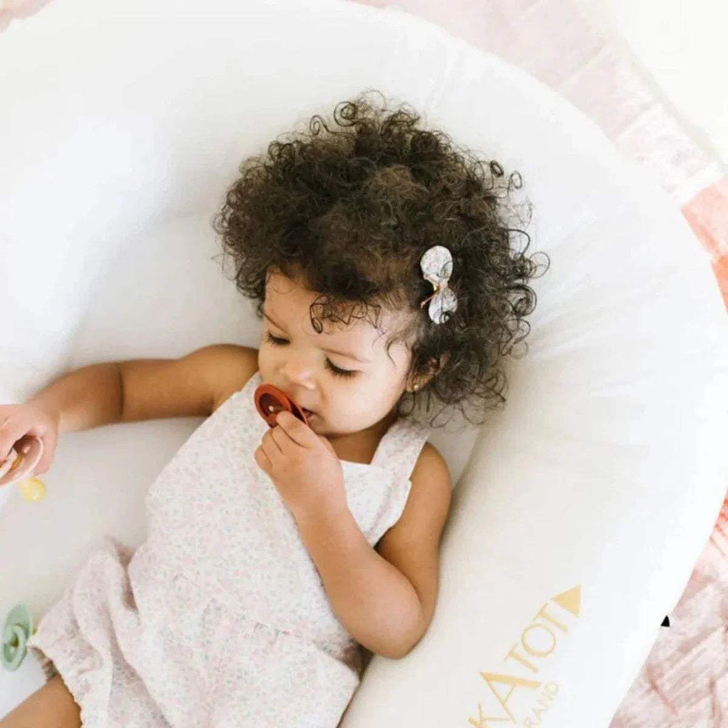 White baby dock with infant resting inside, 'DockATot' logo on side