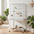 White large bird cage with center divider, perches, and attached storage shelves