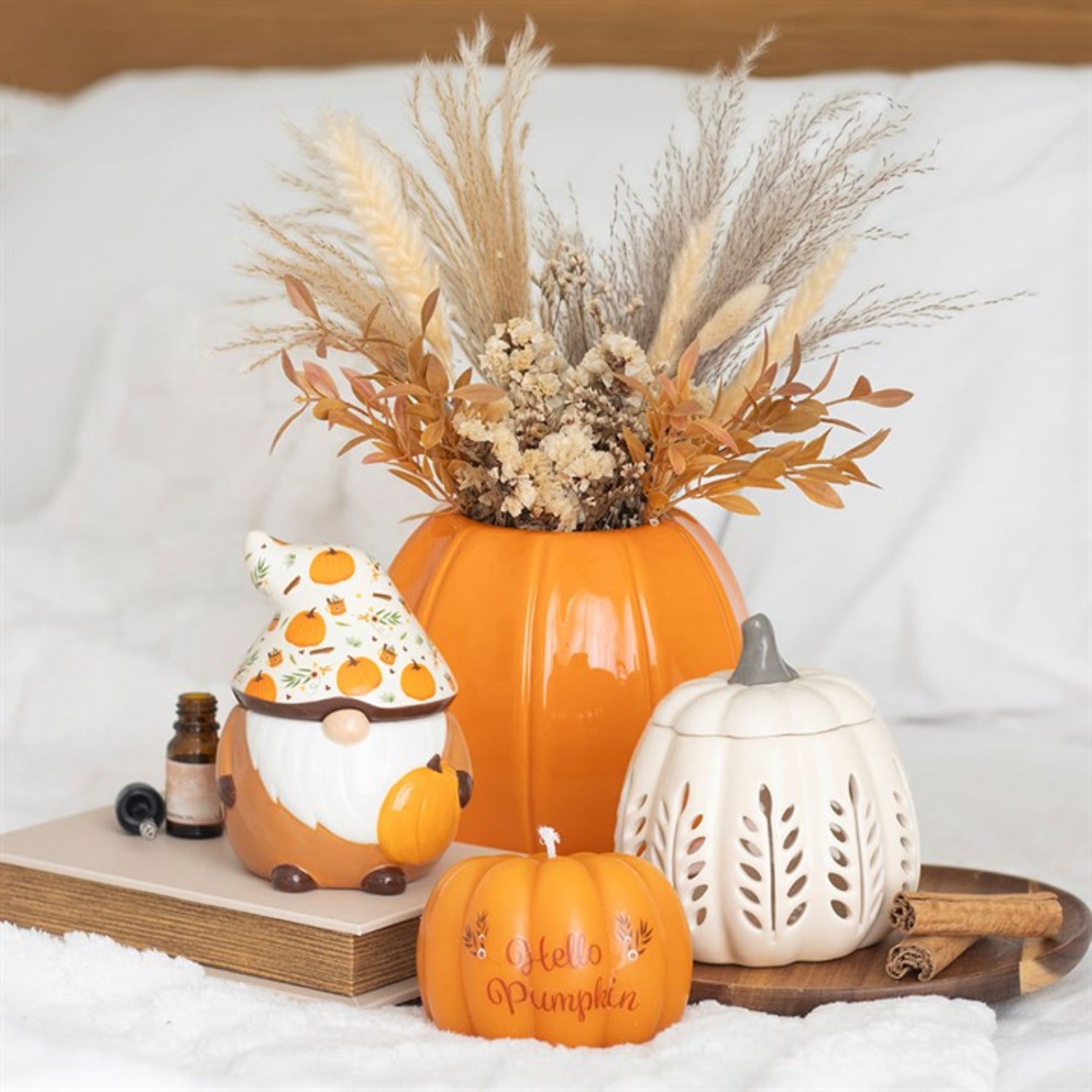 Decorative setup with pumpkins, a gnome, and a lantern on a white surface.