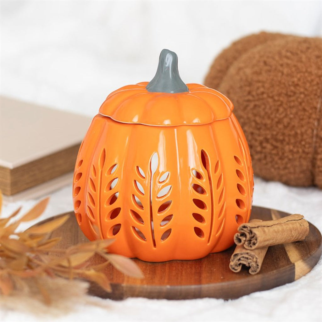 Orange ceramic pumpkin-shaped lantern with a gray top on a wooden surface.