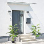 Two potted artificial monstera trees with green leaves in black pots