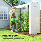 White mini greenhouse with roll-up door opening and tomato plants in garden