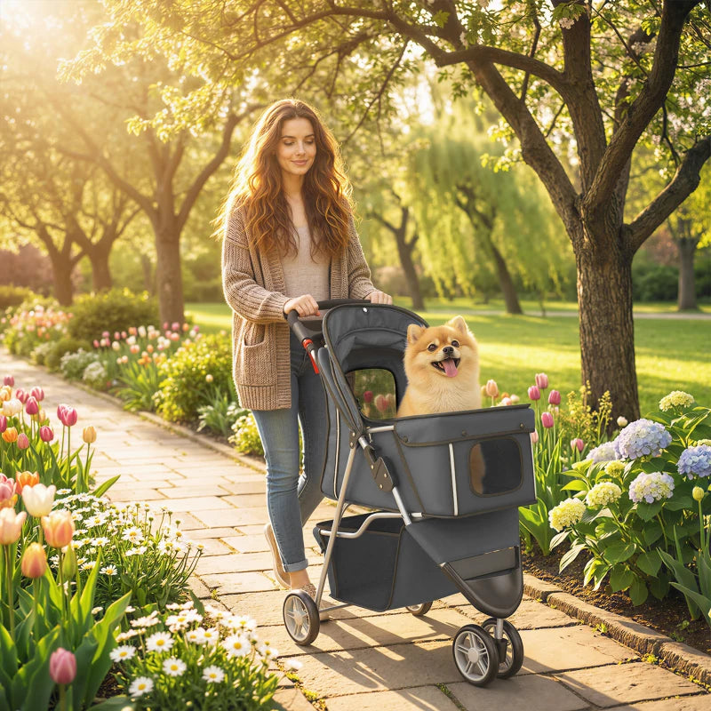 Dark grey 3-wheel pet stroller with canopy carrying a small dog outdoors