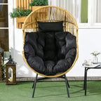 Woven rattan egg chair with thick black cushion, curved back, and armrests