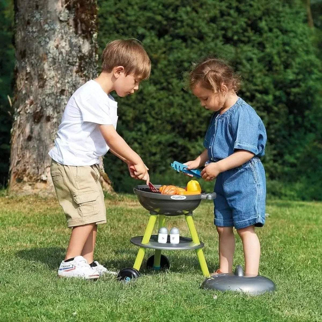 Kids toy BBQ grill with child using spatula; dark lid and lime legs with food pieces