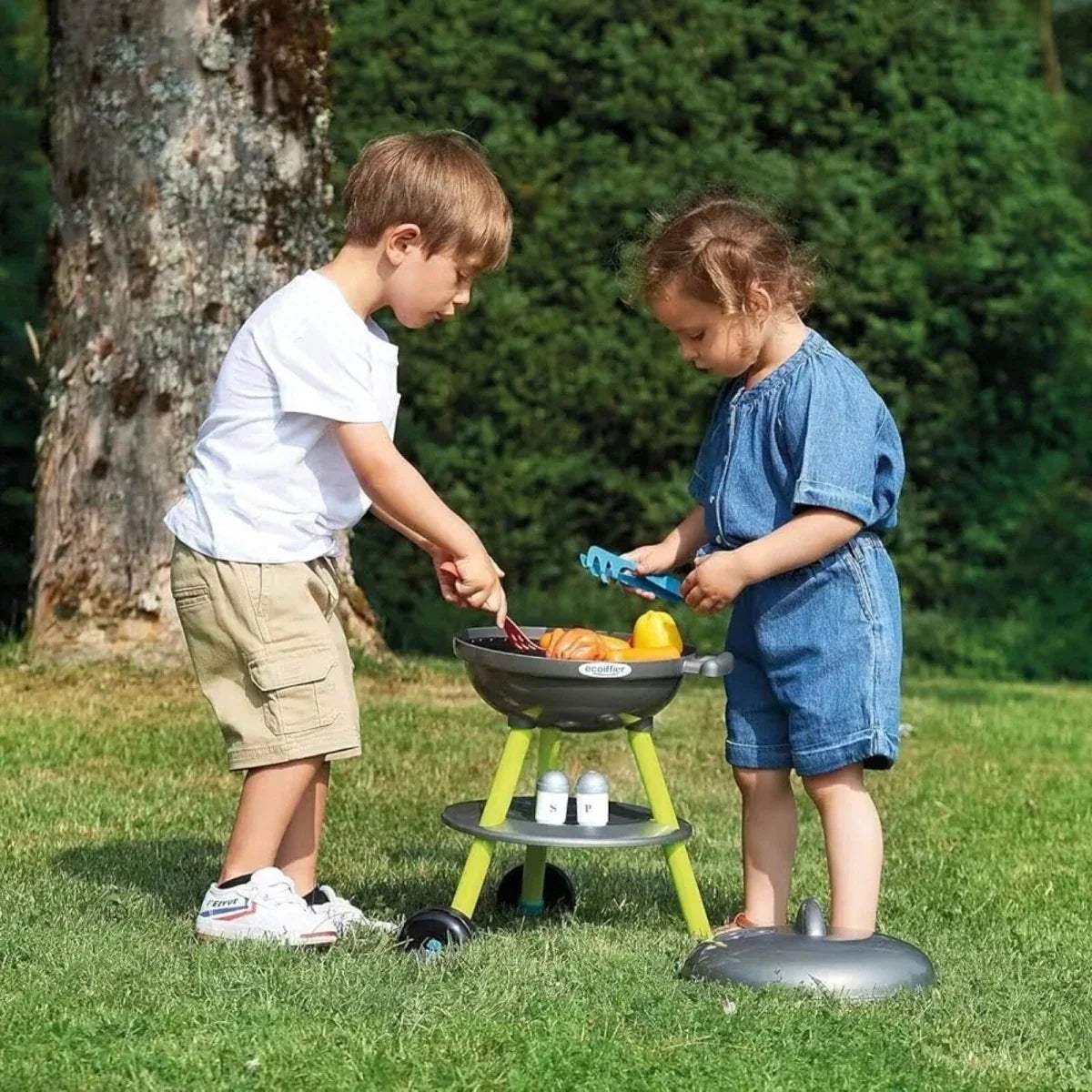Kids toy BBQ grill with child using spatula; dark lid and lime legs with food pieces
