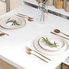 White drop-leaf folding dining table top set with plates, cutlery, and a glass carafe