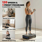 Black vibration plate exercise machine on floor next to standing person using handles