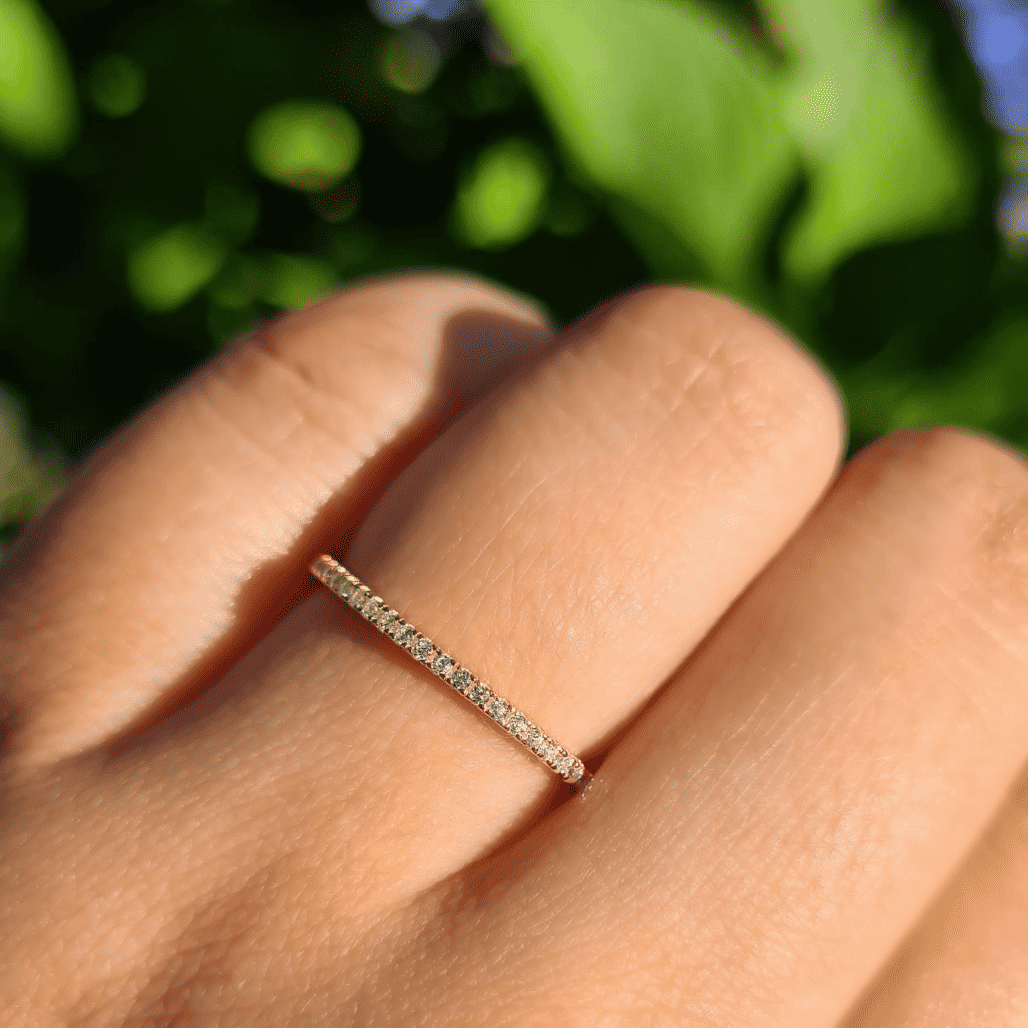 Thin gold eternity ring with pavé stones on a finger