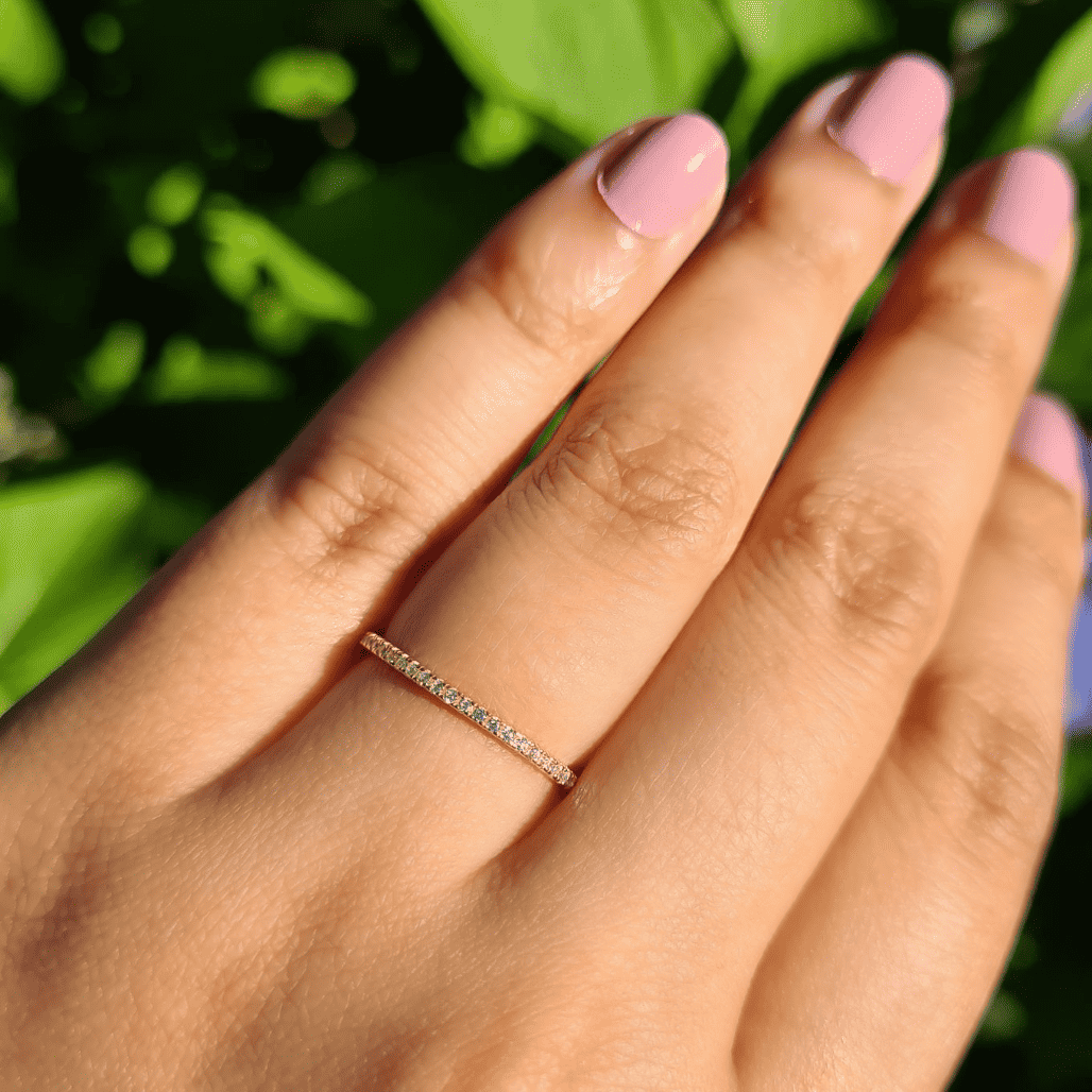 Thin gold eternity ring with small pavé stones on a hand
