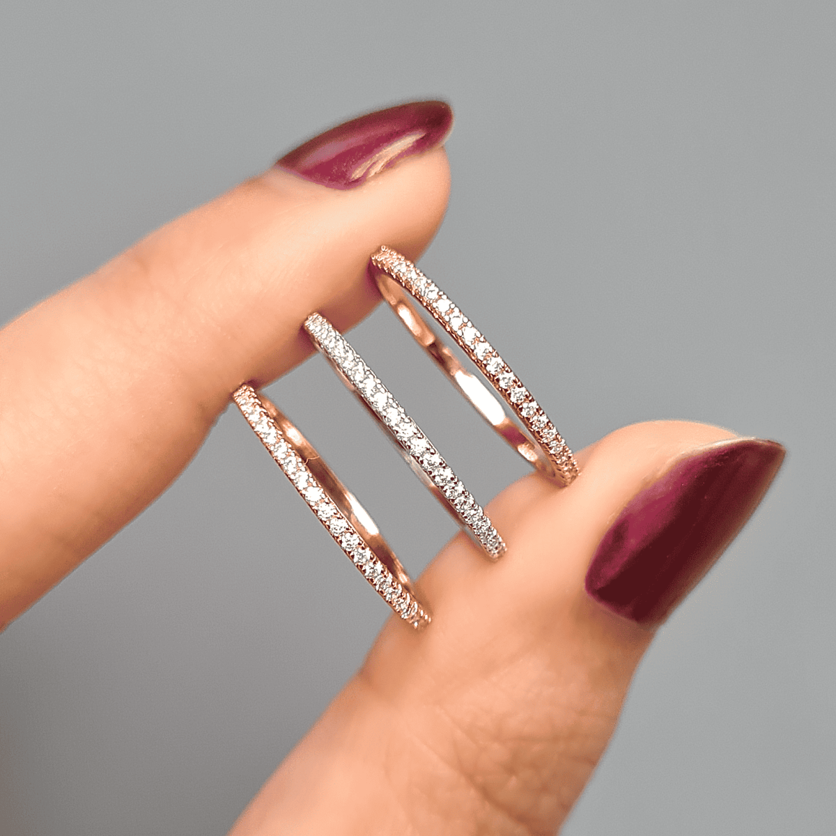 Thin gold eternity ring with pavé stones, shown between fingers