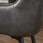 Close-up of grey PU leather side chair seam with stitched padded arm