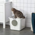 White enclosed litter box with circular front door, cat entering on tiled floor