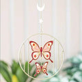 Hanging butterfly ornament on gold-tone circular frame with two pink butterfly cutouts.