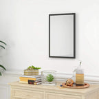 Black framed wall mirror mounted on wall above console table
