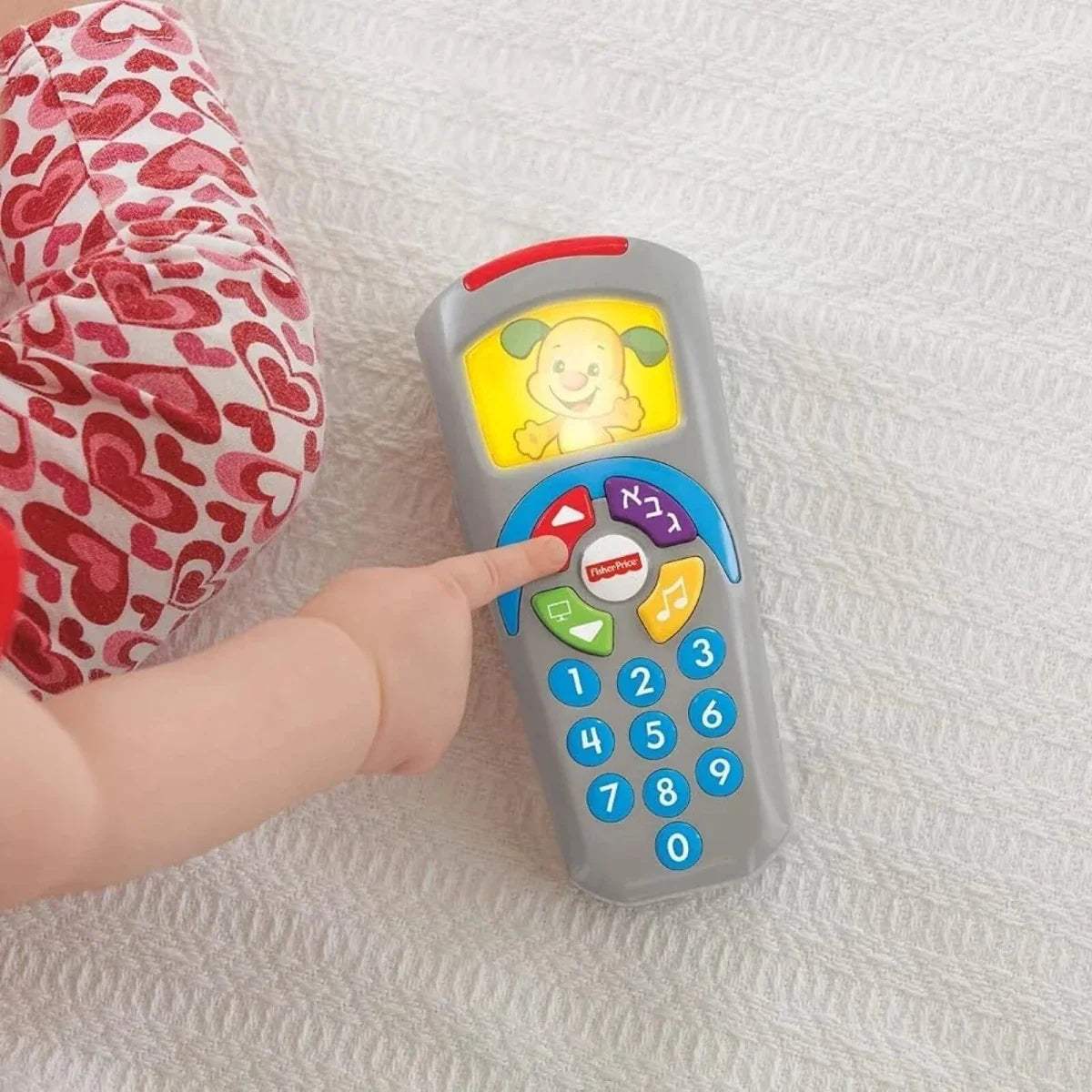 Fisher-Price puppy learning remote in child's hand, gray body with red and blue buttons