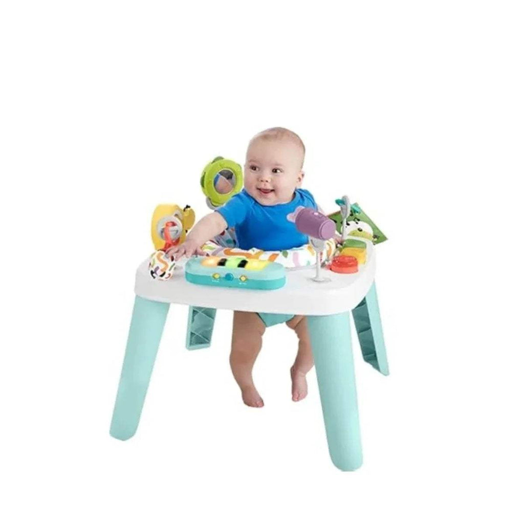 Baby playing at a white-and-teal activity centre table with colorful music toys