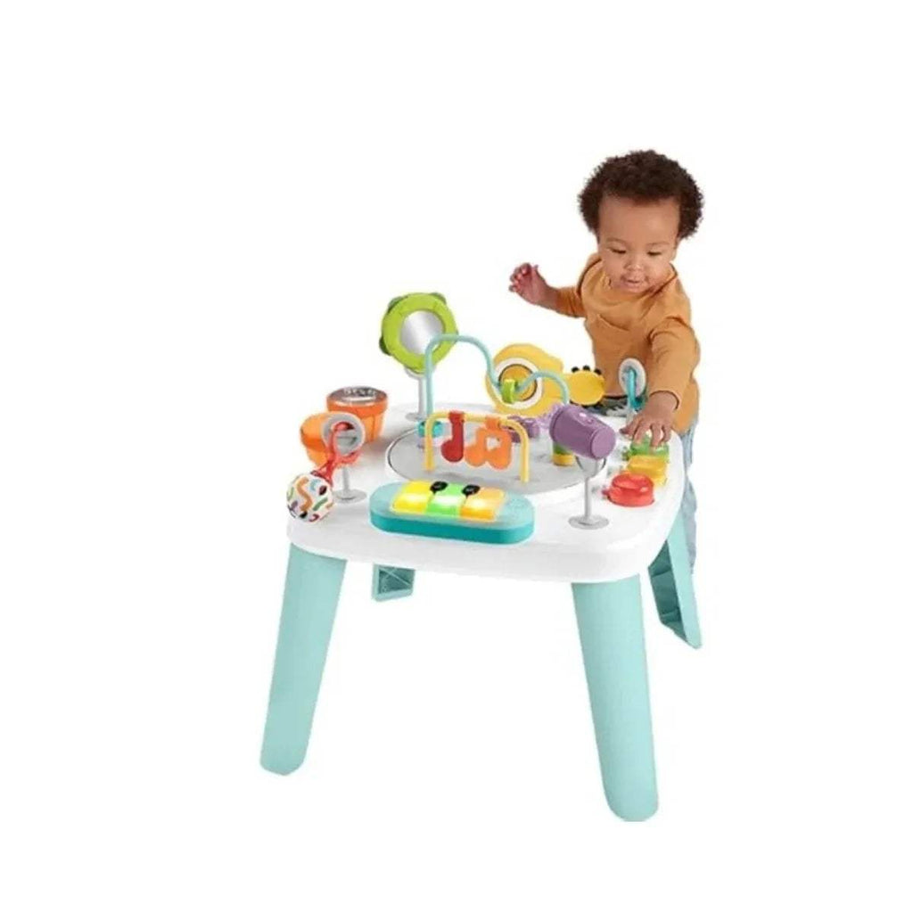 Toddler using a baby activity centre table with multicolor toy play pieces