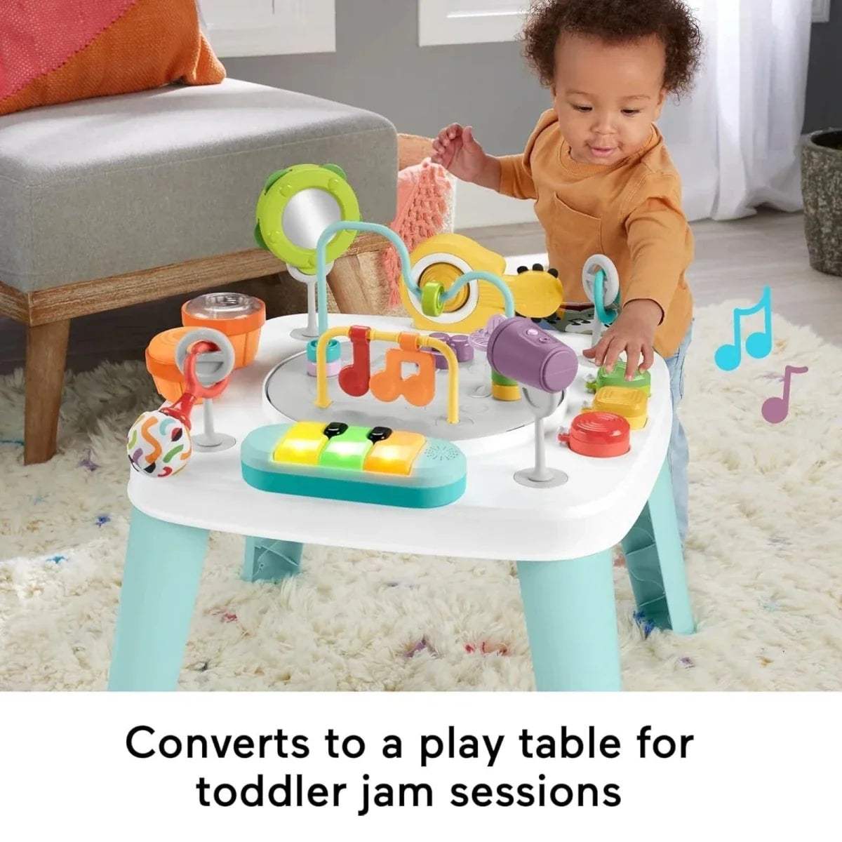 Baby reaching for toys on a white activity centre table with teal legs and push buttons