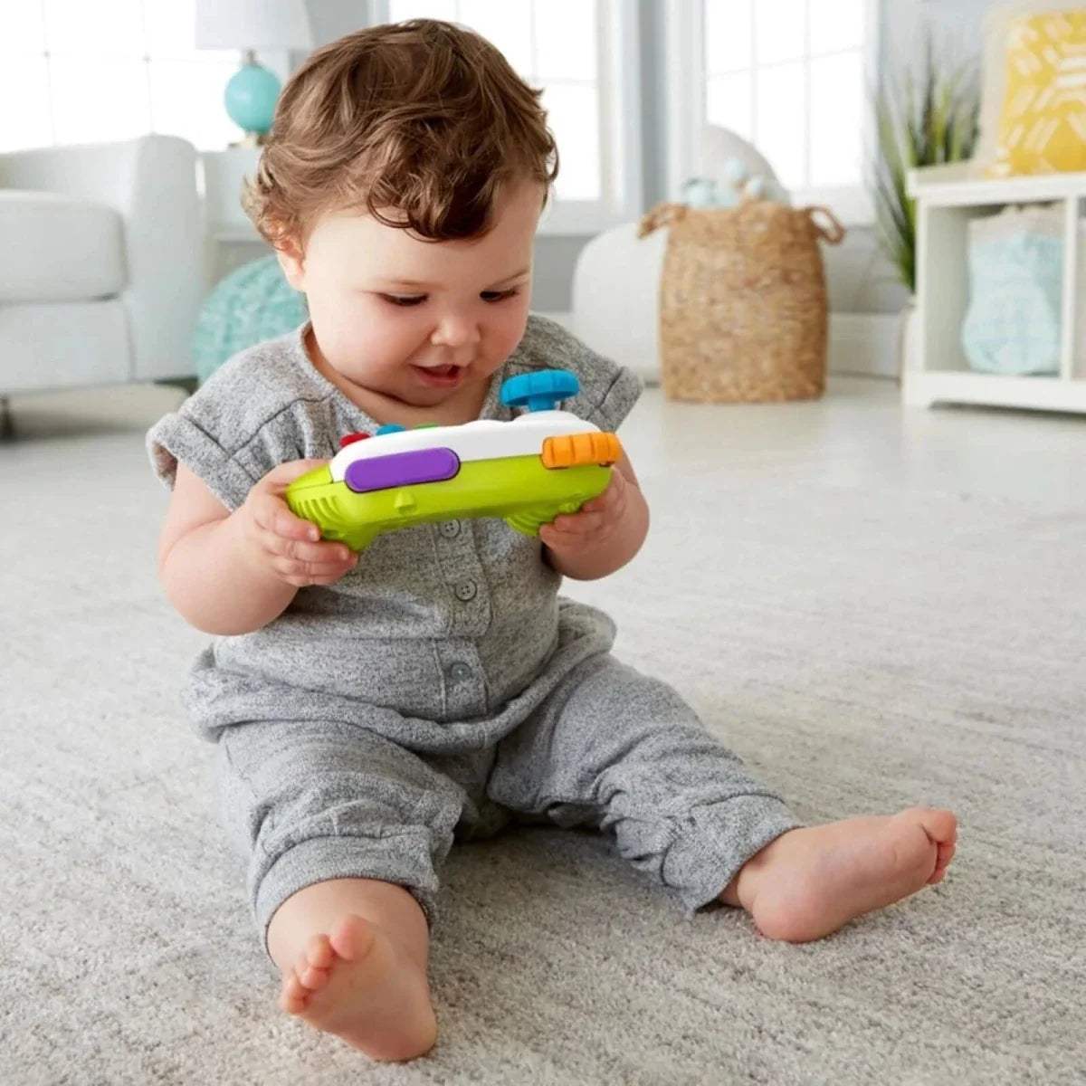 Baby holding green and purple learning controller with colorful buttons and joystick