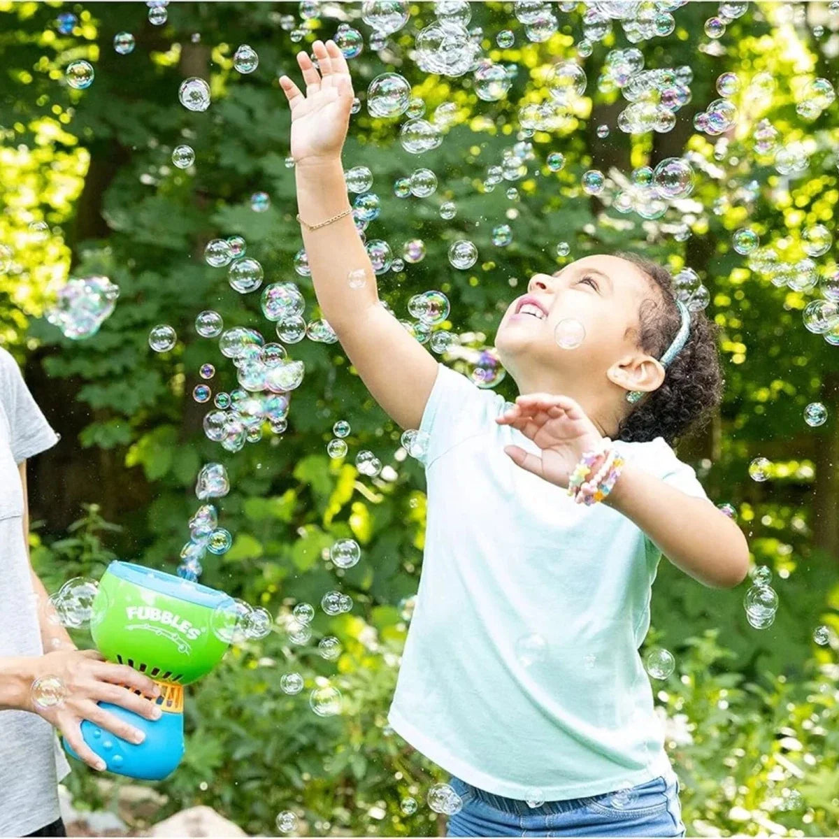 No-spill bubble machine spraying bubbles as a child reaches up outdoors