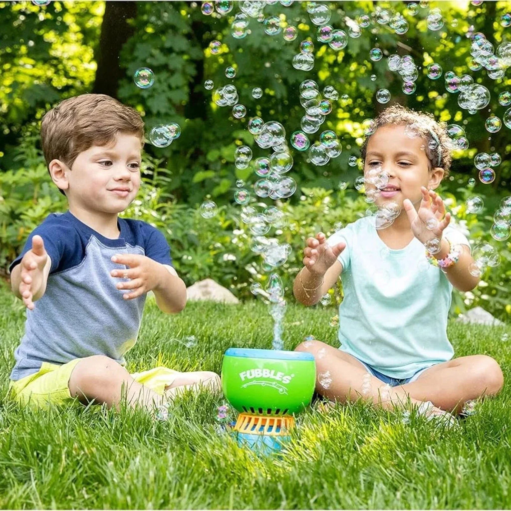 Kids playing with a no-spill bubble machine on grass, bubbles floating around