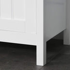 White freestanding tall cabinet on legs, showing bottom frame and door edge