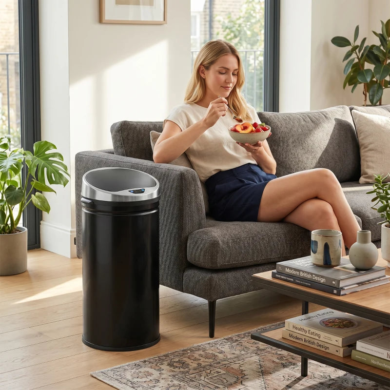 Black 42L motion sensor trash can standing next to sofa in living room