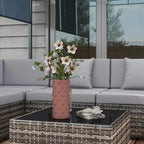 Grey cushion rattan corner sofa set with glass-top coffee table and flower vase.
