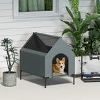 Grey elevated dog house with arched front doorway and mesh-style roof opening; patio view.