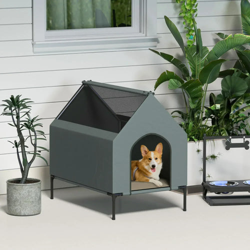 Grey elevated dog house with arched front doorway and mesh-style roof opening; patio view.