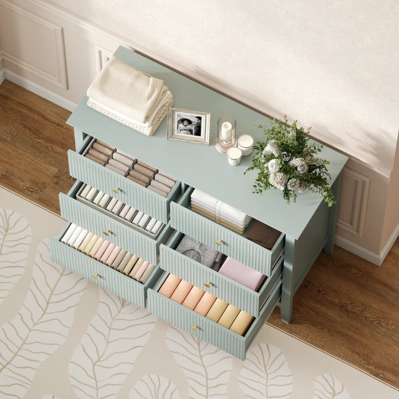 Green fluted dresser with multiple open drawers for organized storage