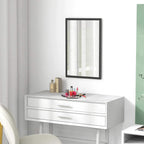 Black framed wall mirror above white vanity with countertop items