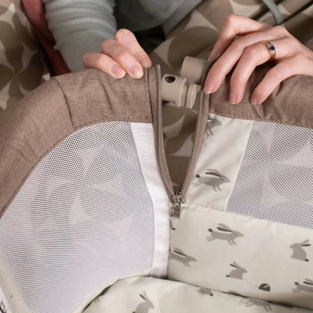 Close-up of zipper and fabric panel on a beige insert inside the bedside crib
