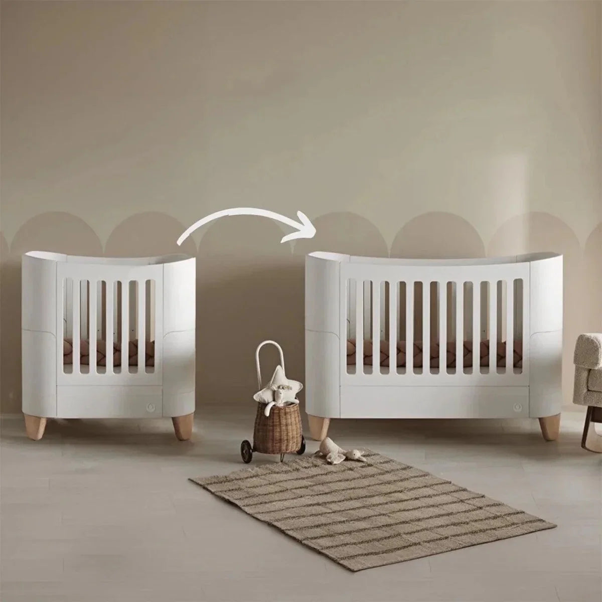 White cot bed set with slatted rails and natural wood legs, two cribs side by side