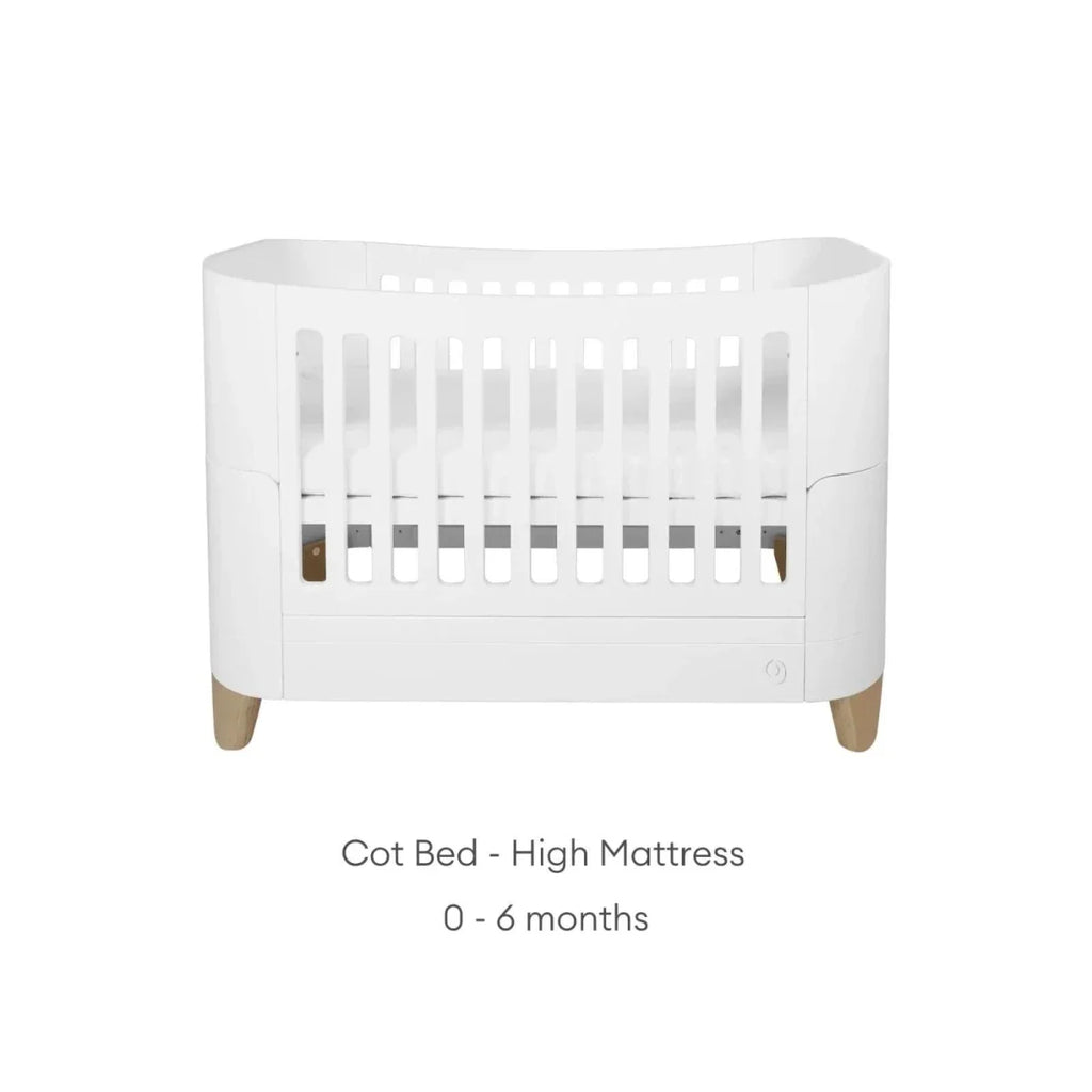 White cot bed with high mattress position, slatted rails and natural wood legs