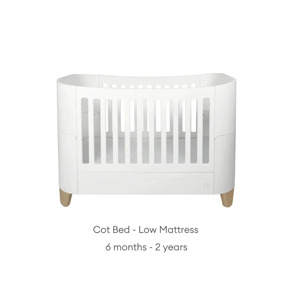 White cot bed with low mattress position, slatted rails and natural wood legs