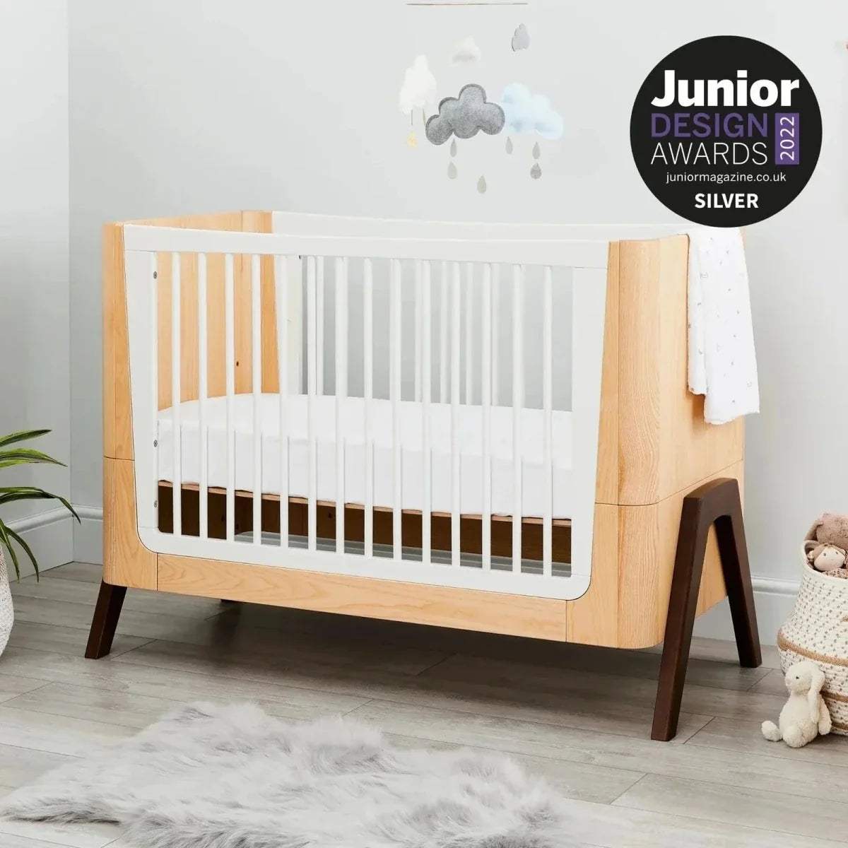 Convertible baby cot bed, natural wood frame with white slatted sides and dark legs