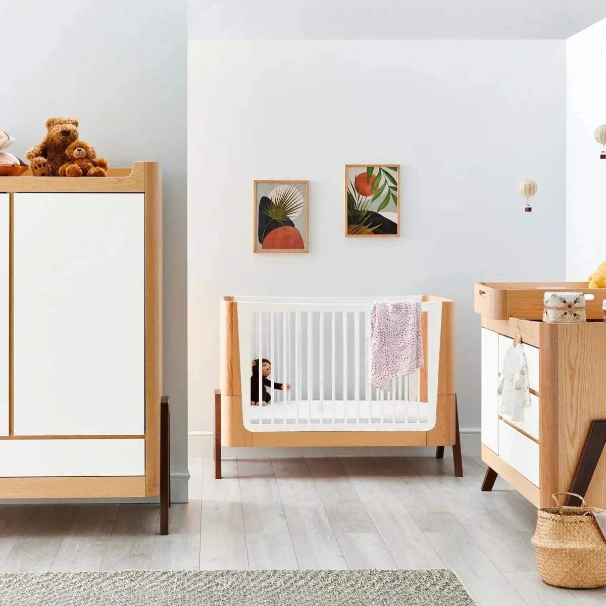 Convertible baby cot bed with white slatted sides, natural wood frame, dark legs